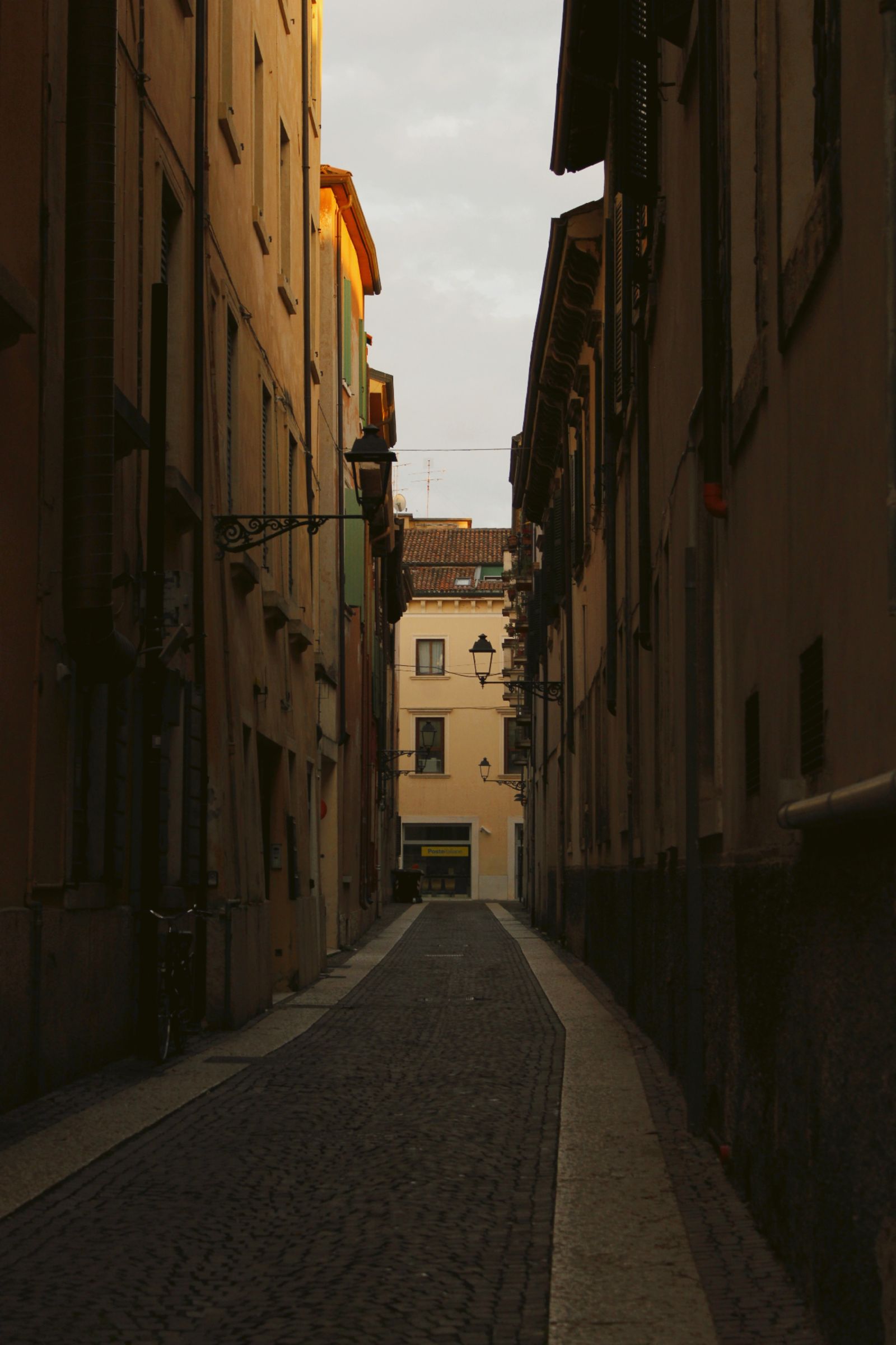 A narrow historic lane in Verona glowing at dusk